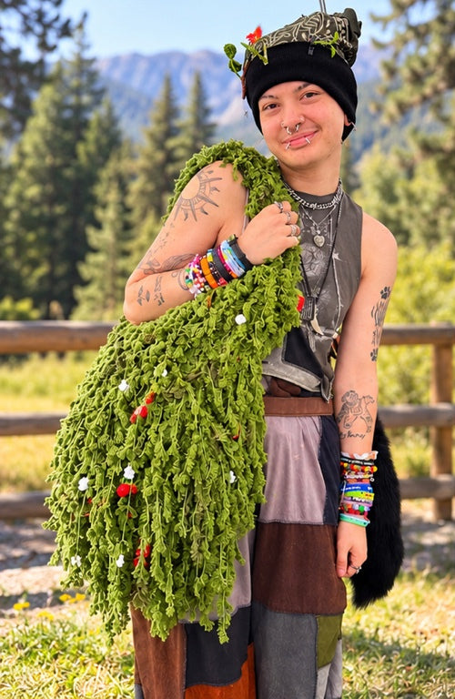 Customer wearing the handmade Strawberry Moss crochet shoulder bag outdoors, with pine trees and mountains behind