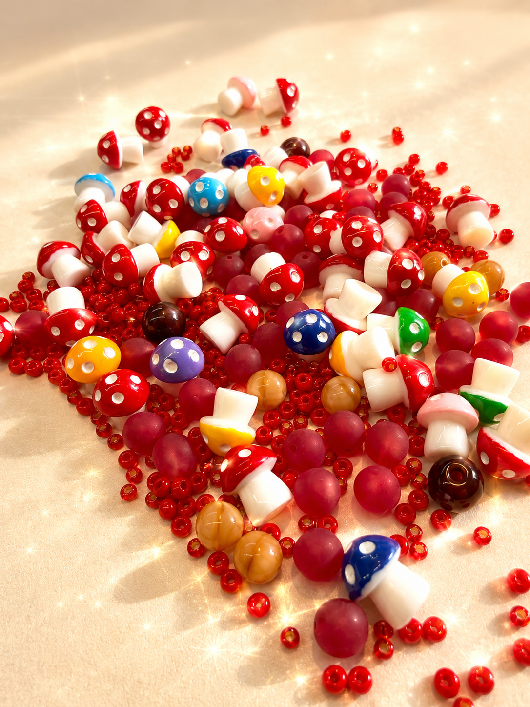 Fungie bead box mix spread on cream fabric — red and white beads with mushroom and strawberry beads.